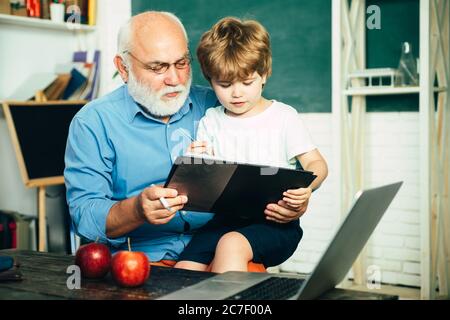 Old and Young. Happy cute clever boy and old tutor with book. Educational process. Family generation and relations concept. Educational process Stock Photo