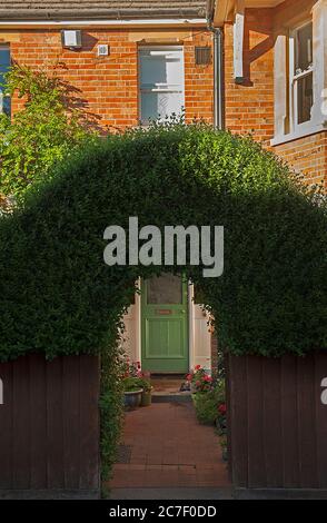 Arched hedge over house gate entrance Stock Photo