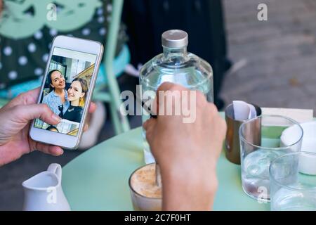 Female hand holding a mobile phone while having coffee looking photos. Stock Photo