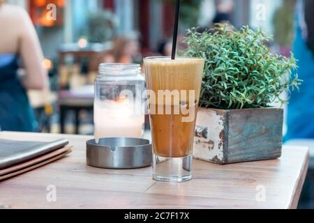 A greek cold coffee, freddo cappuccino placed on a wooden table outdoors. Stock Photo
