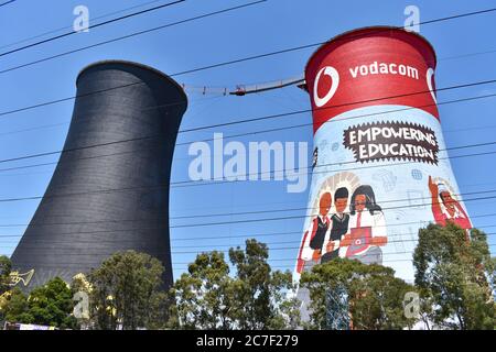 The Orlando Cooling Towers in  a suburb of Soweto. One is brightly decorated with advertising and the other is painted black. Against a clear blue sky. Stock Photo