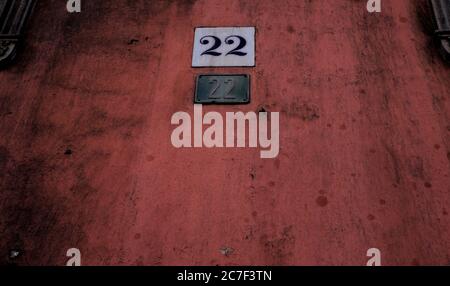 Number 22, twenty-two, two plates on grungy dark wall. Stock Photo