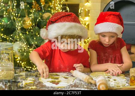 Kids making christmas cookies. Christmas cookies. Two cute boys with santa hat. Cute kids in santa hats preparation holiday dinner for family. Stock Photo