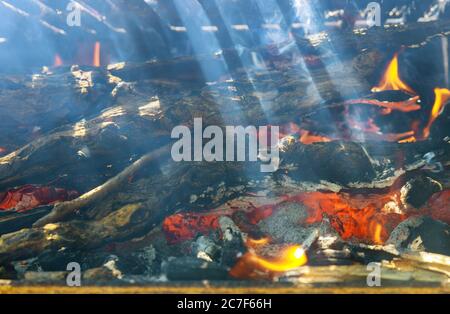 Ray of sunshine through burning firewood metal grill. Close up. Soft focus. Stock Photo