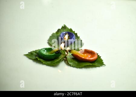 A closeup photograph of three colored Diya or Clay Lamp on a leaf. Stock Photo