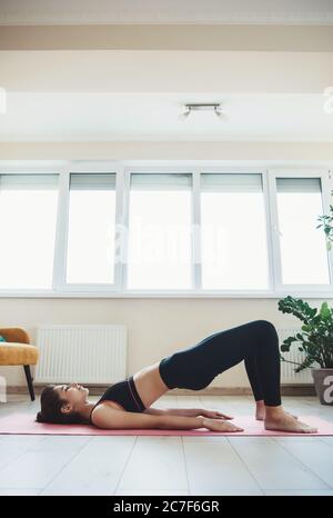 Caucasian woman in activewear doing fitness at home on floor in a light room Stock Photo