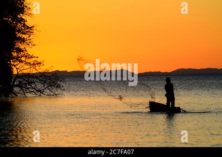 Silhouette of a person on a boat fishing in the sea during sunset in Ometepe, Nicaragua Stock Photo