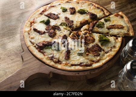 Pepperoni pizza on wooden board, Top view of delicious and crispy vegetarian pizza Margherita on light brown table background Stock Photo