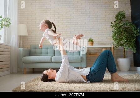 Happy mother's day! Mom and her daughter child girl are playing, smiling and hugging. Family holiday and togetherness. Stock Photo