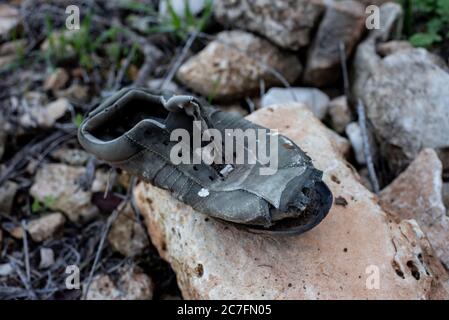 High angle shot of an old and torn out shoe on a rock in the middle of the forest Stock Photo