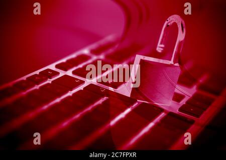 Cool background of an unlocked padlock on a modern keyboard in red-tinted colors - piracy concept Stock Photo