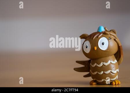 Brown funny owl character standing on a wooden table with a blurry background Stock Photo