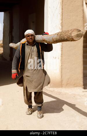 Raghba, Saudi Arabia, February 16 2020: Construction worker in Saudi Arabia carries a construction log on his shoulders. Stock Photo