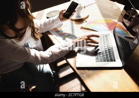 Young business woman working on laptop with phone from home  Stock Photo