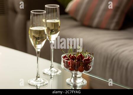 Glasses of sparkling champagne with cherries, close up. Warm colored. Celebration event, holidays, drinks concept. Companion for best family or friend's memories. Anniversary, wedding day or Christmas time. Stock Photo
