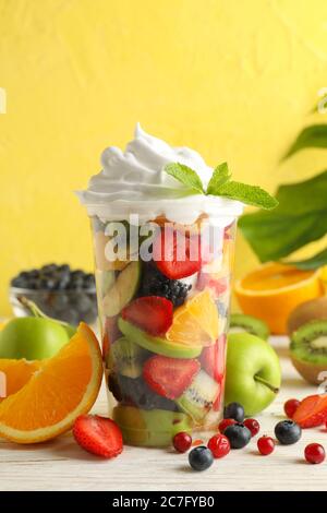Composition with cup of fresh fruit salad on white wooden table Stock Photo