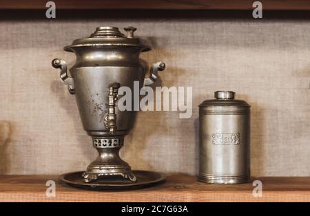 Traditional vintage Russian Samovar, a metal container used to heat and boil water for tea is standing near metal jar. Russian text on the container m Stock Photo
