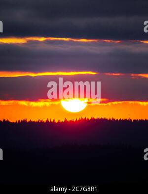 Vertical shot of the beautiful sunset behind the layers of clouds in Oregon Stock Photo