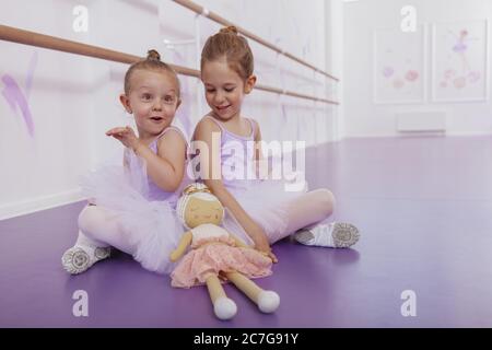 Happy little ballerinas having fun at ballet dance class, copy space. Charming little ballerina girl and her sister exercising at ballet school Stock Photo