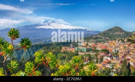 Etna volcano and Taormina town aerial panoramic view. Roofs of a lot of buldings. Smoking snow-capped Mount Etna volcano. Taormina, Sicily, Italy. Stock Photo