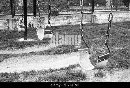Grey scale shot of the swings on the playground in a park Stock Photo