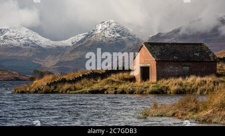 Boat house at Loch Arklet with gathering storm clouds over the Arrochar Alps, near Stronachlachar, Loch Lomond & The Trossachs National Park, Scotland Stock Photo