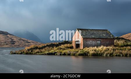 Boat house at Loch Arklet with approaching storm clouds over the Arrochar Alps, near Stronachlachar, Loch Lomond & The Trossachs National Park, Scotla Stock Photo