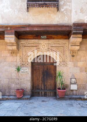 Facade of old stone bricks decorated wall with arched wooden door, Entrance of old Ottoman historic house of Moustafa Gaafar Al Selehdar, Moez Street, Old Cairo, Egypt Stock Photo