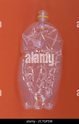 plastic wrinkled bottle against orange background, environment pollution and recycling concept Stock Photo