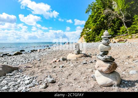 Stacked stones (Cairns) at the pebble beach with chalk cliffs at Piratenschlucht beach at the Baltic sea in Jasmund National Park, Rügen, Germany. Stock Photo