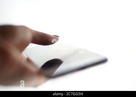 Smartphone in a female hand on a white background. Finger over screen with shadow. Side view, selective focus. Stock Photo