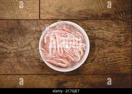 High angle shot of a bowl full of candy canes on a wooden surface Stock Photo