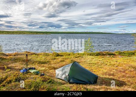 Solo tent at a lakeshore in a wild landscape Stock Photo