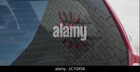 Red clock on a brick wall reflected on a car window Stock Photo
