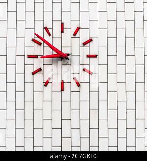 Red clock on a white brick wall Stock Photo