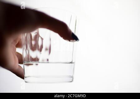 A glass of water in a female hand on a white isolated background. Stock Photo