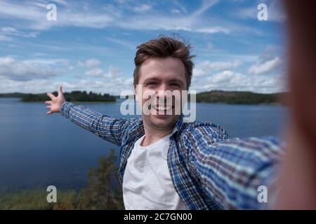 Happy man making a photo of nature and lake. Stock Photo