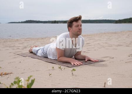 Man doing Cobra Yoga Stretch on yoga mat Stock Photo