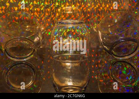 Glass tumblers on reflective base against a kaleidoscope of colours Stock Photo