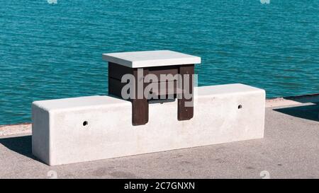 An isolated wooden table with a marble seat on the harbor quay (Pesaro, Italy, Europe) Stock Photo