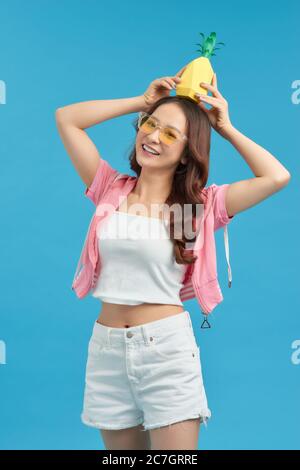 Attractive happy young woman holding fresh pineapple with a smile. Stock Photo