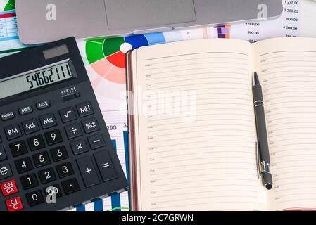 Calculator and an empty Notepad page on the desktop with financial papers. Pen, calculator, and laptop. Top view with a copy of the text input space Stock Photo