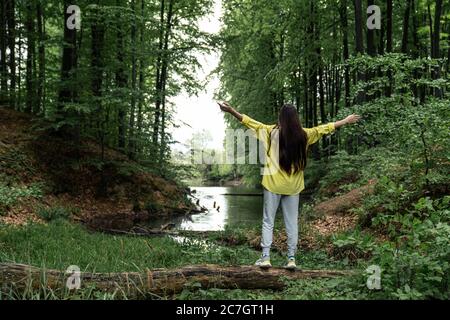 Young woman balances on a tree log near the lake Stock Photo