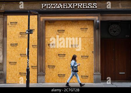 Glasgow, Scotland, UK. 17 July, 2020.  Images from Glasgow city centre as covid-19 restrictions are relaxed and  the public are out and about shopping and at work. Pictured; woman walks past closed and boarded up Pizza Express restaurant. Iain Masterton/Alamy Live News Stock Photo