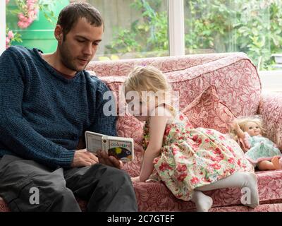 Toddler and uncle learning about colours from a book, UK Stock Photo