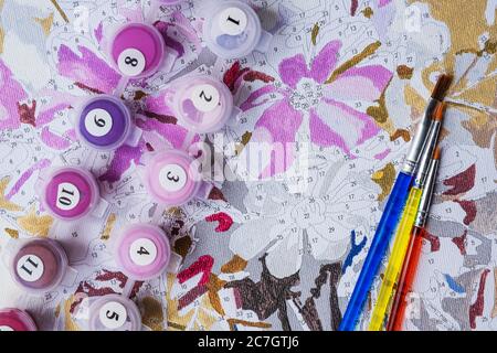 Painting by numbers. Drawing on canvas. Numbered paint cans and brushes. Creative hobby. Flat lay Stock Photo