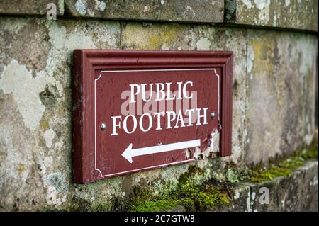 An old distressed Public Footpath sign on an old stone wall. Stock Photo