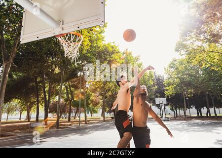 two young men play basketball outdoors Stock Photo