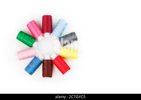 Sewing threads of different colors on reels on a white background in a circle. Stock Photo