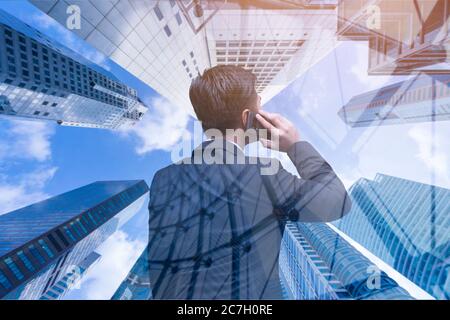 Manage et and telecommunication concept, Businessman using phone against business district buildings in modern city Stock Photo